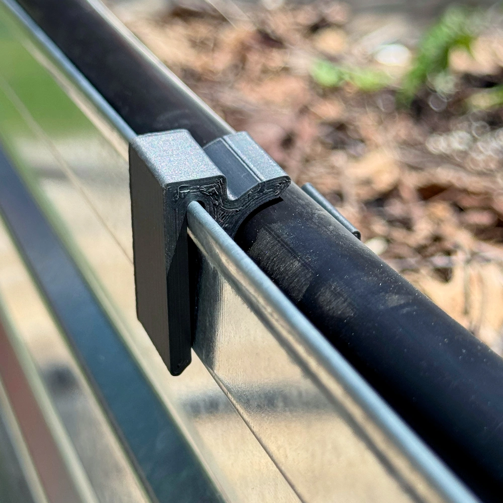 The finished 3D printed clip holding irrigation tubing in the garden bed
